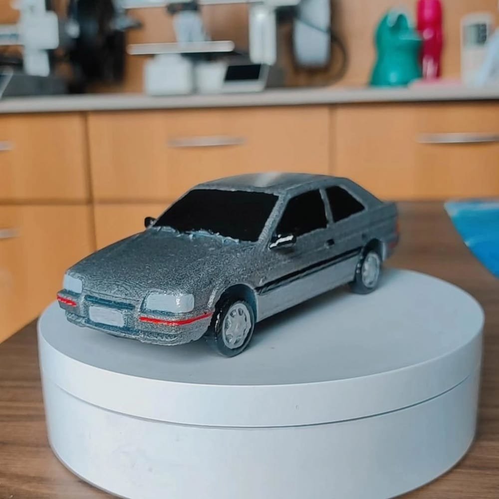 A mesma miniatura do Ford Escort vista de três quartos dianteira, com o friso vermelho do para-choque pintado