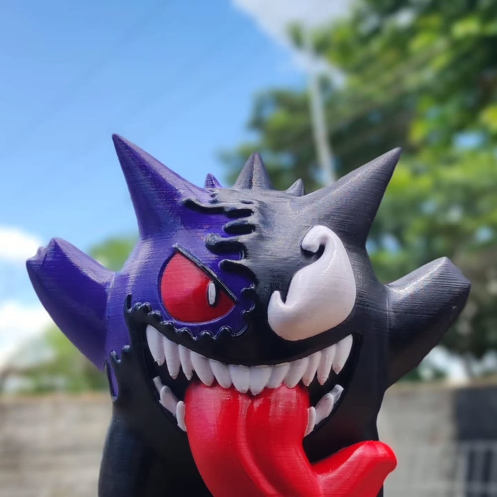 Figura grande do Gengar pintada à mão em roxo e preto, com a língua vermelha para fora, ao ar livre