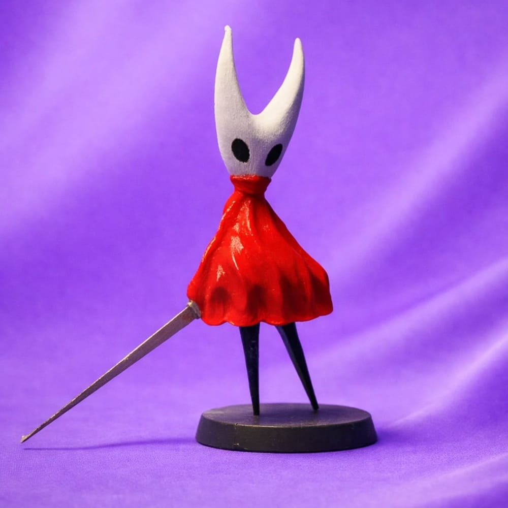 Figura da Hornet, de Hollow Knight, com capa vermelha e agulha, sobre base preta e fundo roxo