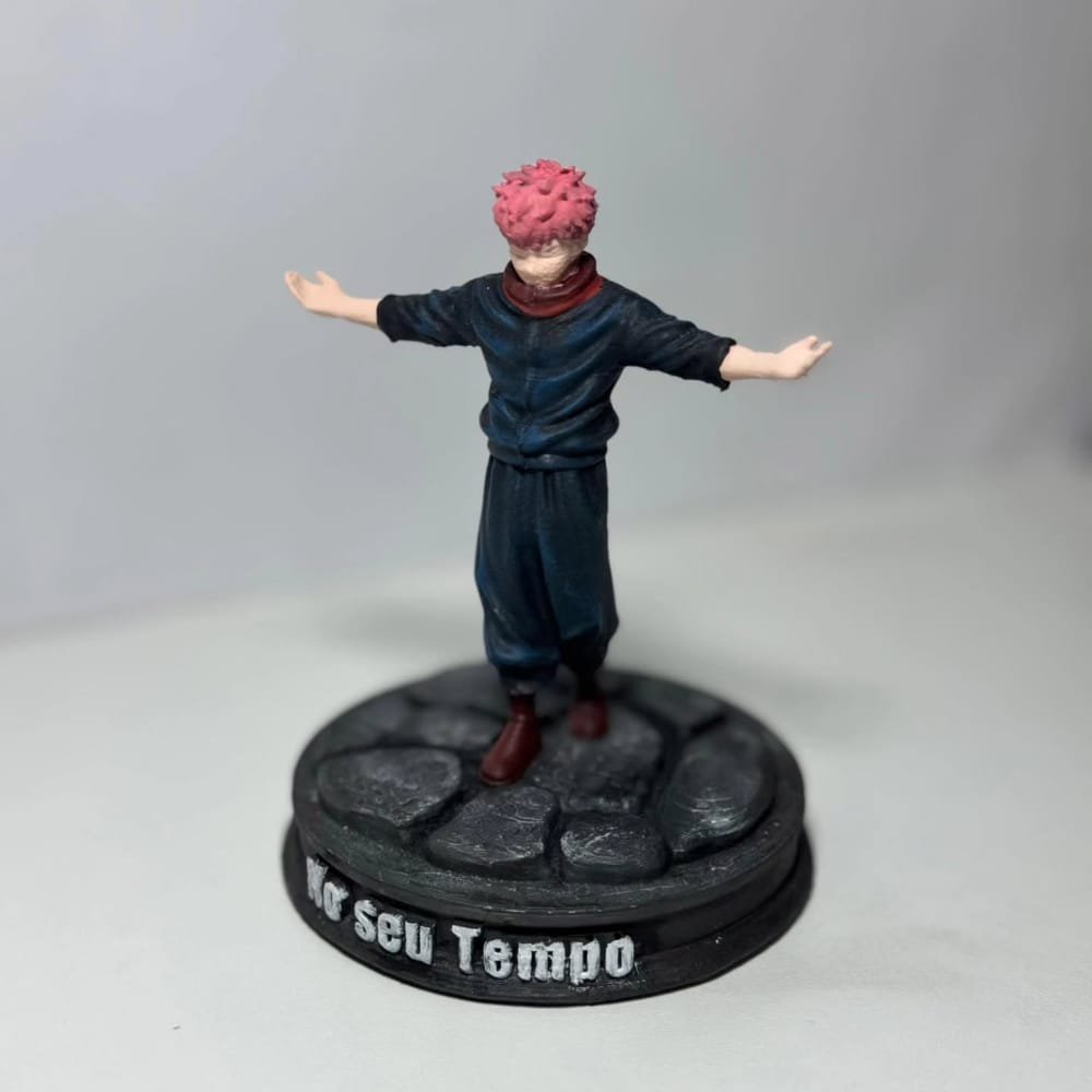 Figura do Yuji Itadori de braços abertos, sobre base de pedra com a frase No seu Tempo em relevo