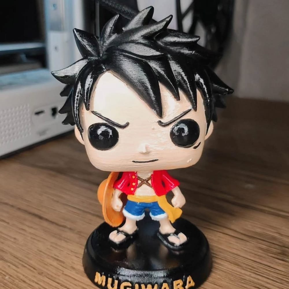 Boneco do Luffy, de One Piece, com chapéu de palha nas costas, sobre base preta com a palavra MUGIWARA